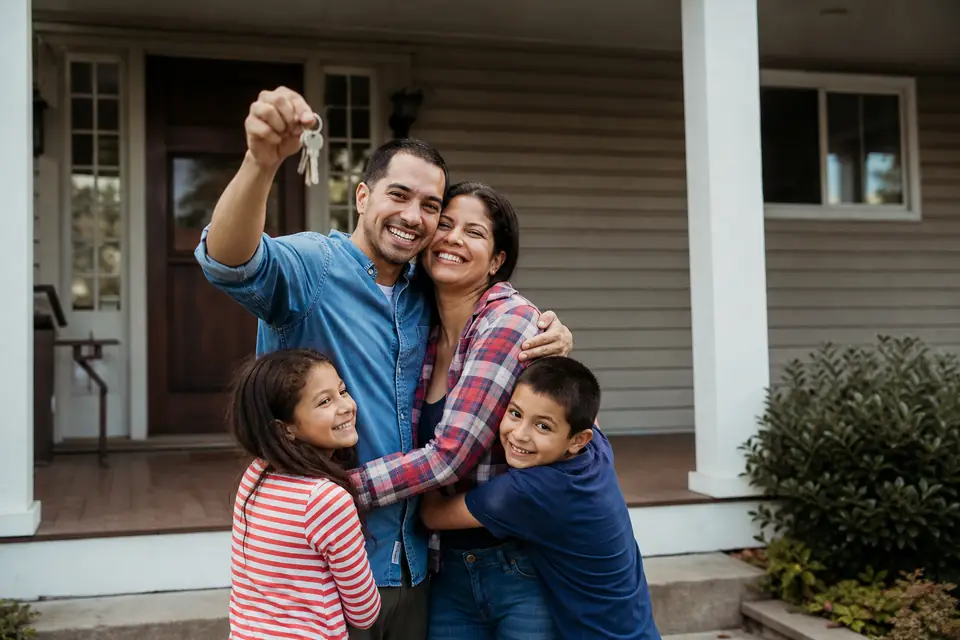 Familia muestra las llaves de su nueva casa en el porche