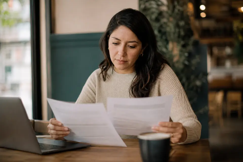 Mujer compara dos ofertas de préstamos personales en la mesa de un café